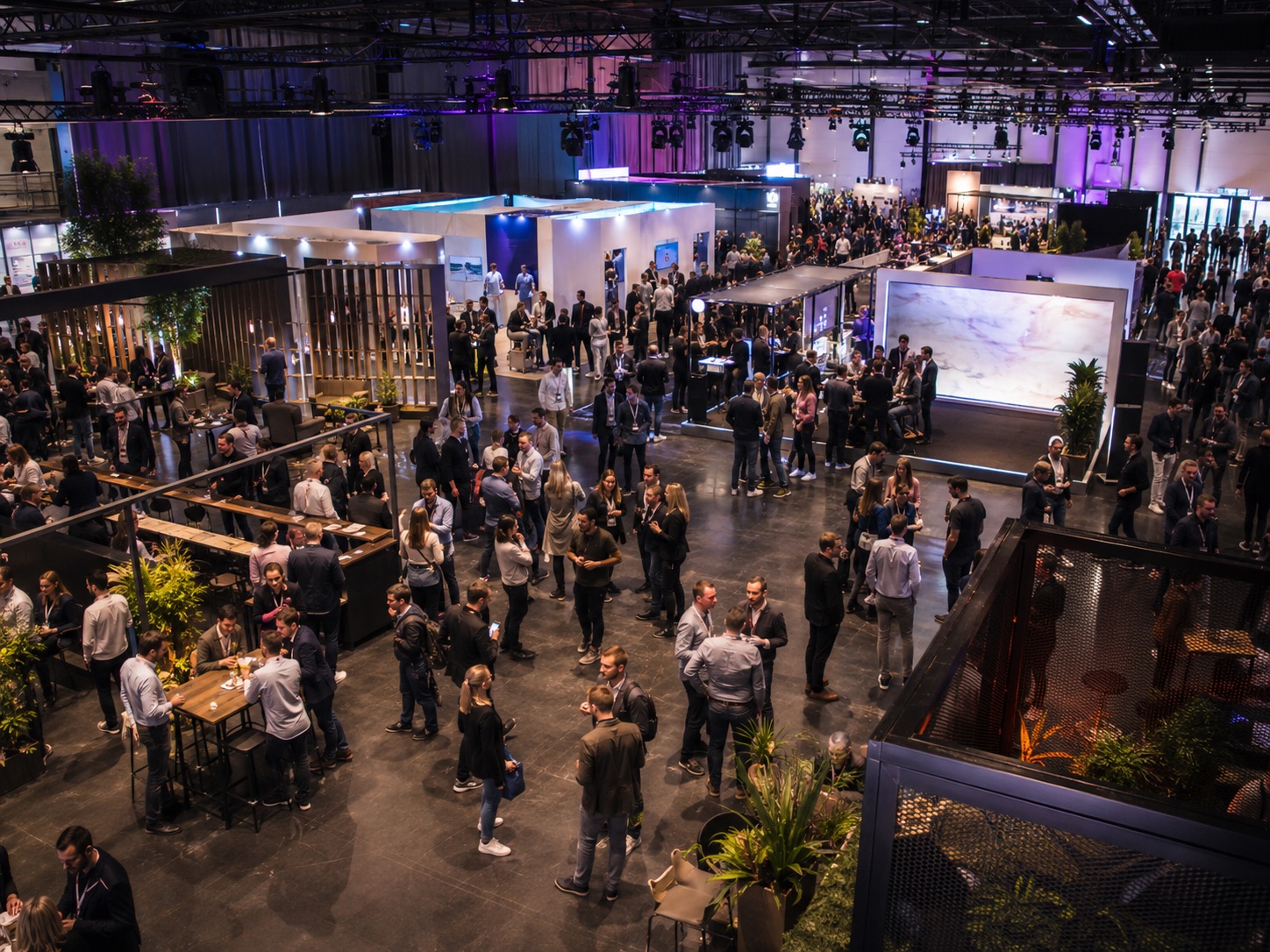 KI-generiertes Symbolbild einer gut besuchten Messehalle mit Networking-Bereichen und Ausstellungsständen
