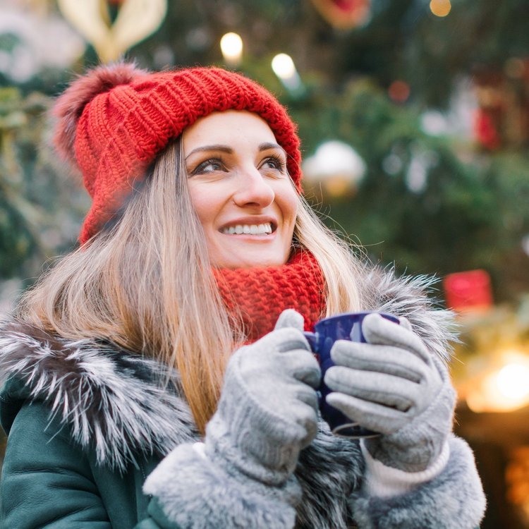 Frau mit roter Mütze genießt heißen Punsch auf dem weihnachtlichen Gänsemarkt in Hamburg