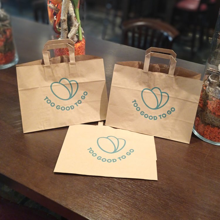 "Too Good To Go" paper bags on a table at the Park-Hotel Hagenbeck restaurant – promoting sustainable food waste reduction