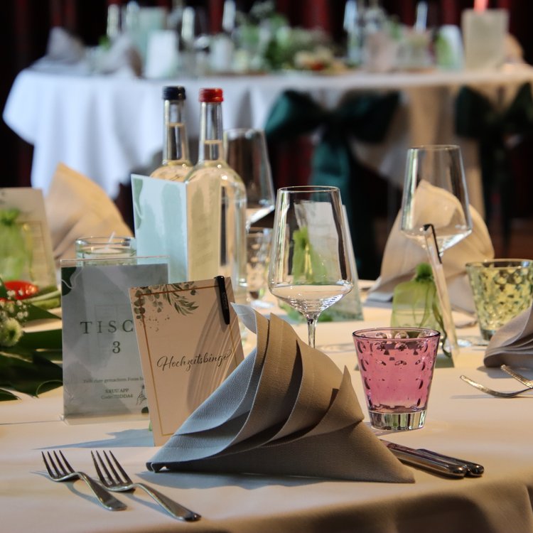 Festlich gedeckter Tisch mit eleganten Servietten, Gläsern und Blumenschmuck bei einer Hochzeitsfeier im Park Hotel Hagenbeck in Hamburg.