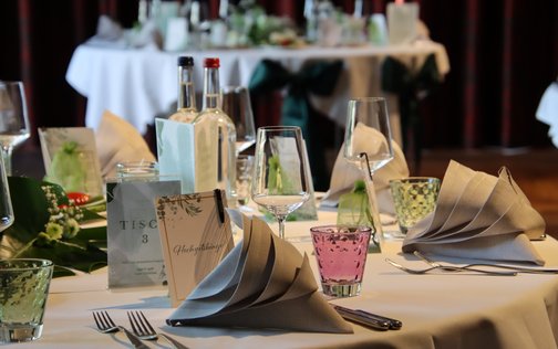 Festlich gedeckter Tisch mit eleganten Servietten, Gläsern und Blumenschmuck bei einer Hochzeitsfeier im Park Hotel Hagenbeck in Hamburg.
