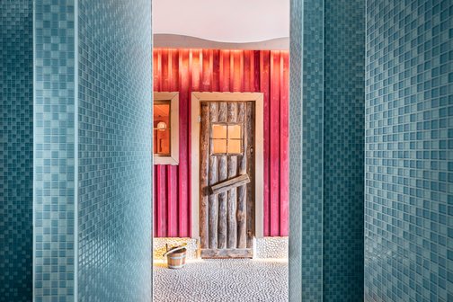 Blick aus der Dusche auf die farbenfrohe Saunahütte im Park-Hotel Hagenbeck